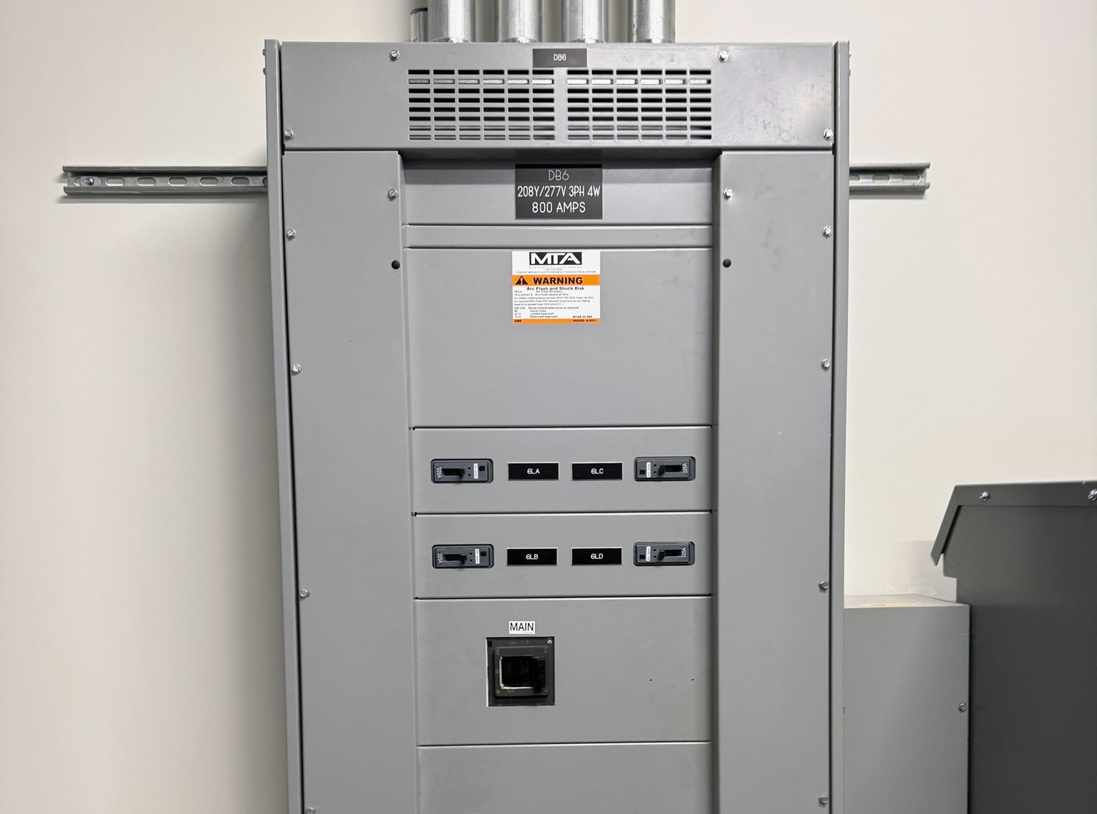 Close view of the Violet project 800-amp distribution panel, labeled breakers and metal conduit.