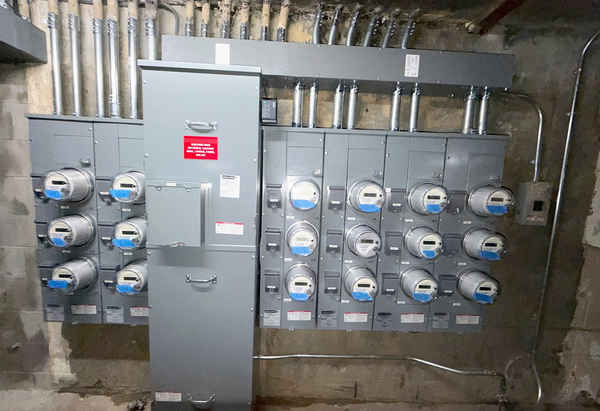 Wide view of the Summertime Section B meter bank, central service cabinet and conduits entering above the equipment.